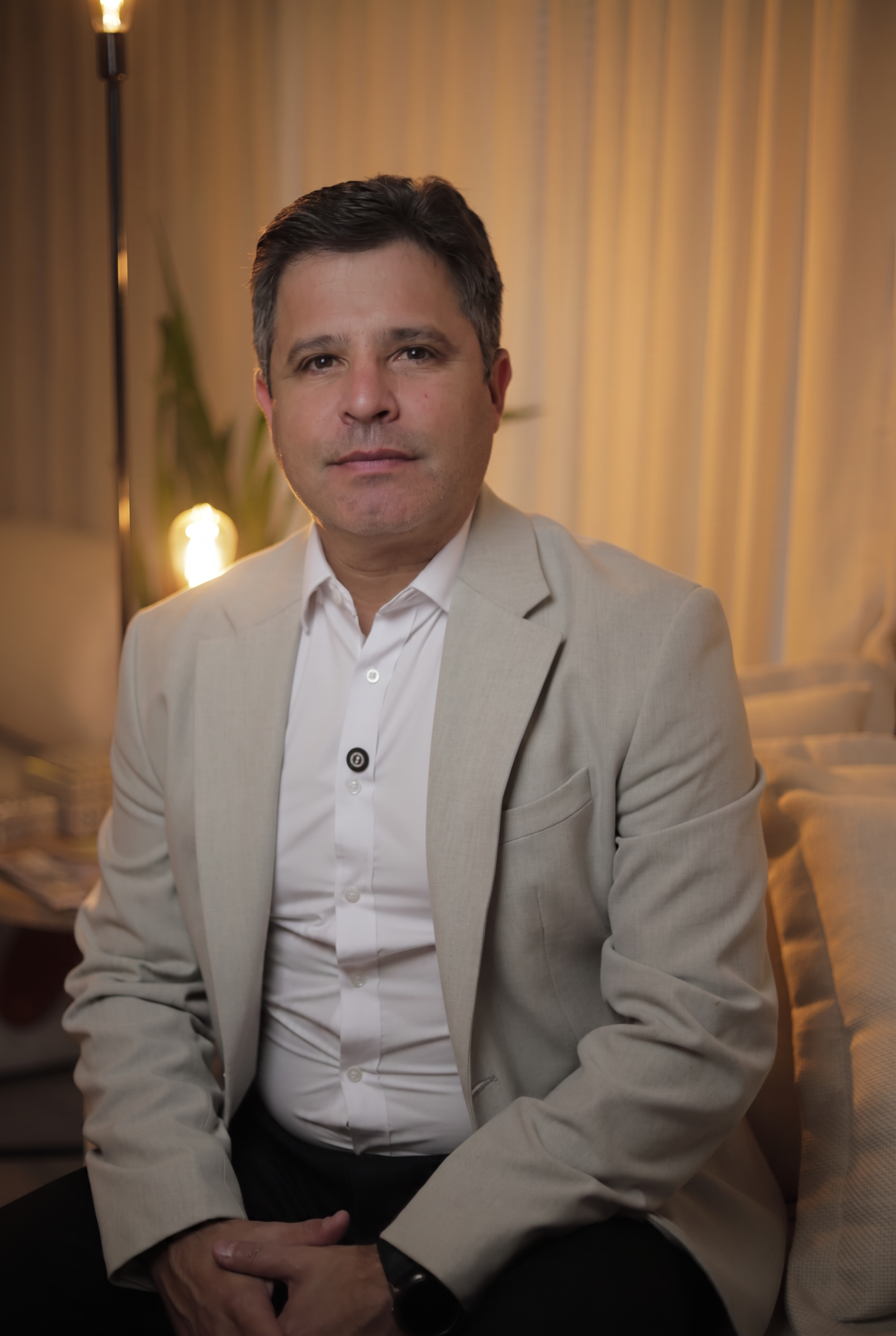Retrato profissional do Dr. Carlos Eduardo Cury Jr. sentado, usando blazer bege